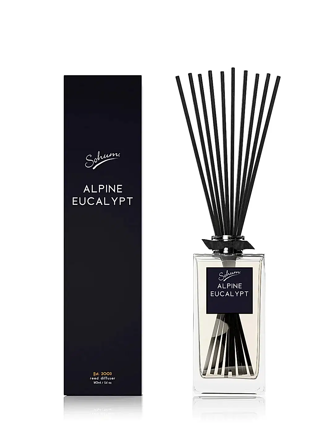 A minimalist black and white fragrance diffuser labeled "Sohum Fragrance Diffuser" from Flowers on Norton St exudes elegance. The glass bottle, featuring natural fiber reeds, sits beside its matching rectangular box. Both display sleek, modern typography, offering a fine fragrance that complements any decor.