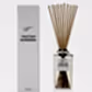 A bottle of the Sohum Fragrance Diffuser by Flowers on Norton St sits elegantly next to its matching white box. Filled with a fine fragrance and topped with natural fiber reeds, it's designed to elevate home ambiance through exquisite fragrance diffusion.