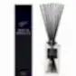 A black, rectangular box labeled "Flowers on Norton St Sohum Fragrance Diffuser" stands beside a clear glass reed diffuser bottle. Designed for fine fragrance lovers, the bottle features natural fiber reeds extending from it, enhancing the pleasing aroma with its light-colored liquid.