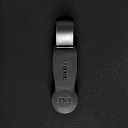 A sophisticated black hat clip from the "Accessories by Klipsta" collection, featuring an elegant design, prominently showcasing the name "KLIPSTA" and a raised "KI" logo, all gracefully contrasted against a dark backdrop, crafted by Flowers on Norton St.