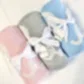 The set includes three Ellie Baby Blankets from FlowersonNortonSt in pink, gray, and blue, each adorned with a white ribbon and a small "kids" label tag. Crafted for supreme softness, these blankets are elegantly displayed against a white background.