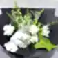The "Under the Limelight" bouquet from Flowers on Norton St features a stunning combination of white roses, lilies, and orchids, expertly arranged with greenery and lime anthuriums against a sleek black wrapping. The bouquet is elegantly displayed on a light gray textured surface.