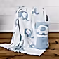 A cuddly Ellie Baby Blanket by FlowersonNortonSt, featuring a white base with blue elephants, drapes over a chair. It is accompanied by another Ellie Baby Blanket rolled up and tied with a white ribbon, both set gracefully on a wooden floor against a pristine white backdrop.