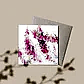 The Native Botanical Greeting Card by Flowers on Norton St showcases pink and purple Australian native birth flowers in watercolor, partially inside a plain brown envelope. The beige background with soft branch shadows adds to its delicate charm.