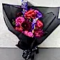 The Hot Pink Pop Mixed Flower Bouquet from Flowers on Norton St features a striking combination of vibrant purple, pink, and magenta blooms. These stunning seasonal flowers are elegantly wrapped in black paper with a matching ribbon at the base, all beautifully presented against a light-colored surface.