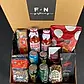 The "Celebration in a Box" by Flowers on Norton St includes two jars of Don Antonio's Sugo di Pomodoro alla Calabrese, a pack of chips, Torta Pistocchi cake, assorted espresso capsules, mixed almonds, and several beverage cans. Everything is neatly arranged in a cardboard box with "F+N gifting" on the lid. Enjoy same-day delivery in Sydney.