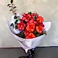 The Only Roses Bouquet by Flowers on Norton St features vibrant Colombian roses and orange flowers wrapped in white paper with a black ribbon. Green leaves enhance the blooms, beautifully set against a light gray textured background, ready for delivery across Sydney.