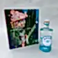 An "Amalfi Moment Gift Box" by Flowers on Norton St is placed beside the book "Slim Aarons: La Dolce Vita," featuring a cover adorned with stunning images of an Italian lakeside villa encircled by tall trees and a tranquil boat on the water.