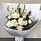 The Serenity Sheath by FlowersonNortonSt features a delicate arrangement of white roses and daisies accented with sprigs of greenery, elegantly wrapped in white paper and tied with a ribbon, creating a graceful sympathy tribute against a light gray background.