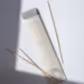 A package labeled "Incense Sticks | Peggy Sue Co." by Flowers on Norton St rests on a light surface. Four sandalwood incense sticks are scattered nearby, while sunlight casts a shadow across part of the scene, creating a serene and minimalist composition.