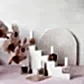 Bottles of MISS FRANKIE nail polish by Flowers on Norton St are elegantly arranged in various shades on a white geometric staircase against a pastel pink backdrop. To the left, pink orchids complement the setting, while a white, arched decor in the background enhances the soft and sophisticated aesthetic.