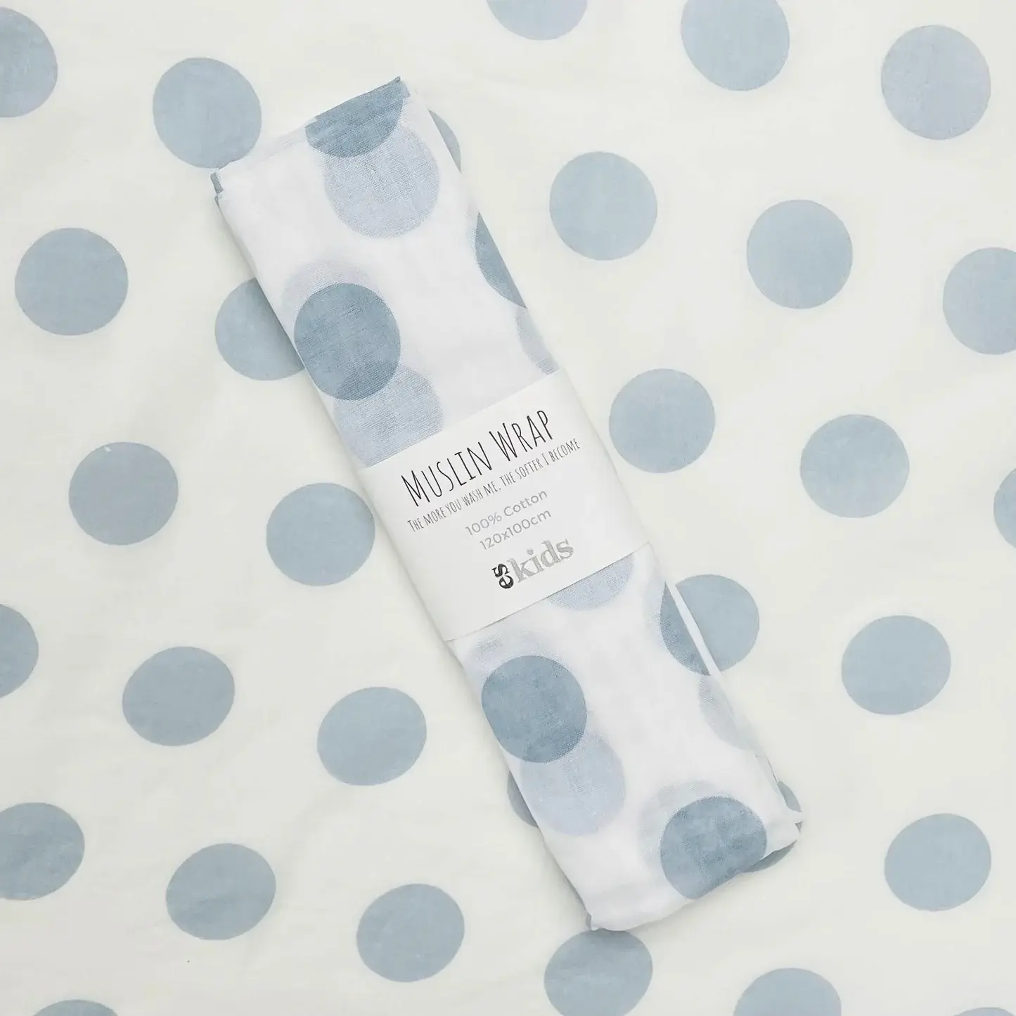 A rolled Muslin Wrap by FlowersonNortonSt, featuring blue polka dots on a matching background, is perfect for wrapping a baby.