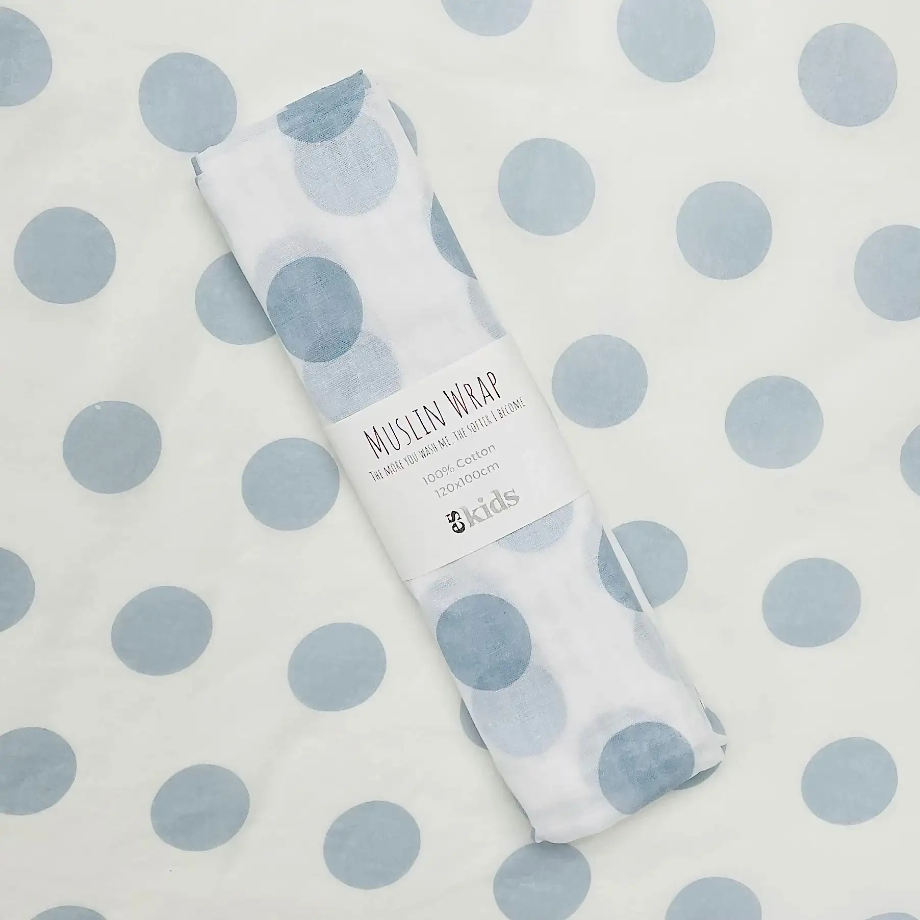A rolled Muslin Wrap by FlowersonNortonSt, featuring blue polka dots on a matching background, is perfect for wrapping a baby.
