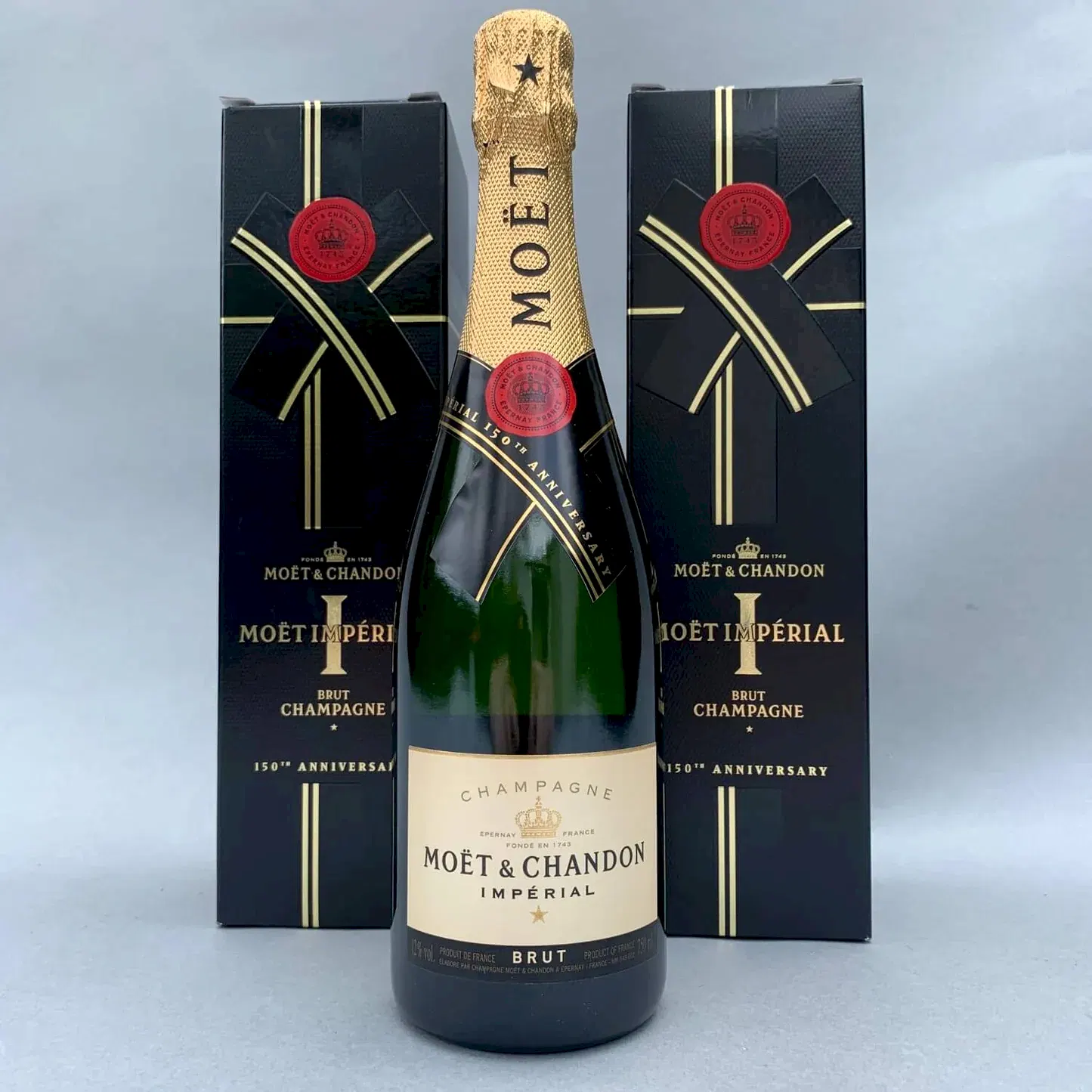 A bottle of Moët & Chandon, representing FlowersonNortonSt's distinctive style, is showcased against a light gray background. It is stylishly accompanied by two black and gold boxes, highlighting the renowned champagne with its gold foil top and the brand's traditional label.