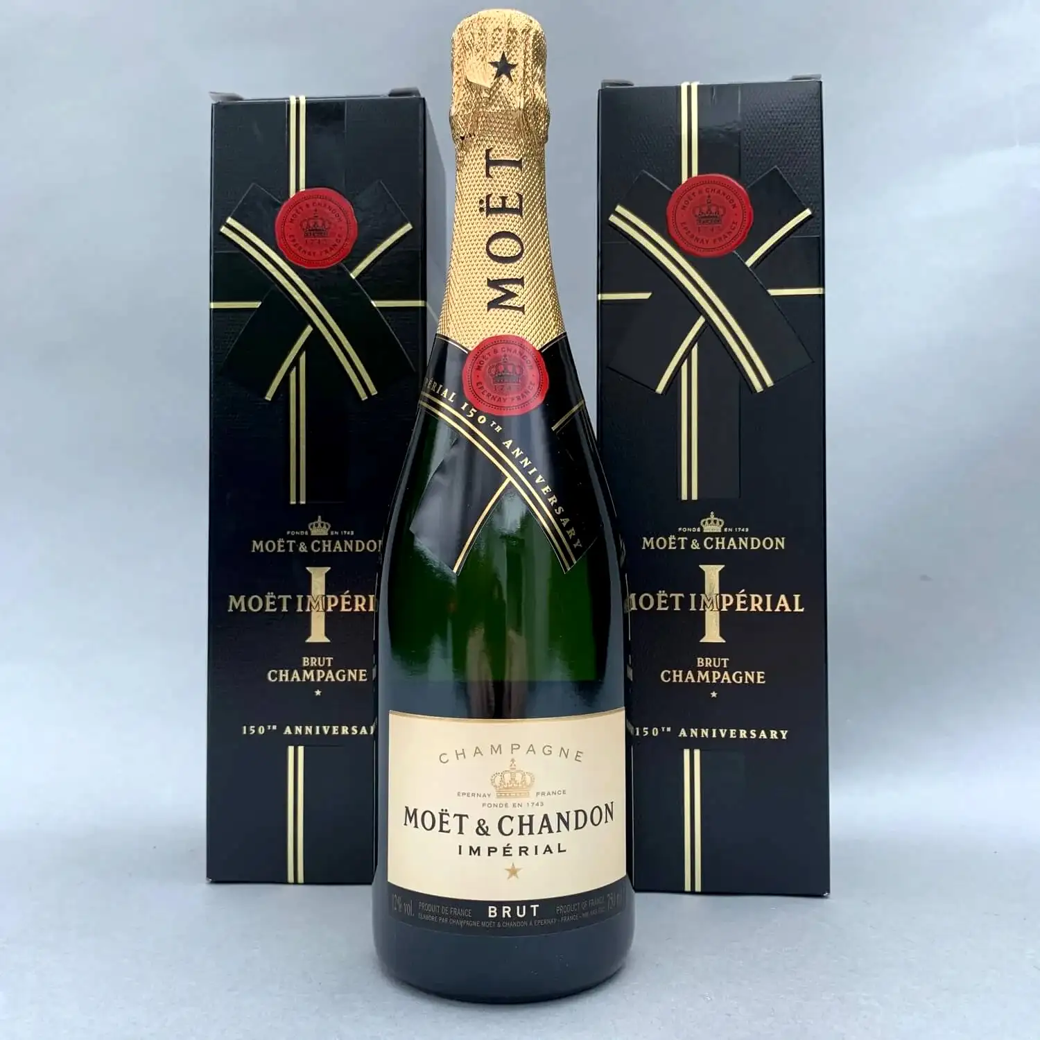 A bottle of Moët & Chandon, representing FlowersonNortonSt's distinctive style, is showcased against a light gray background. It is stylishly accompanied by two black and gold boxes, highlighting the renowned champagne with its gold foil top and the brand's traditional label.