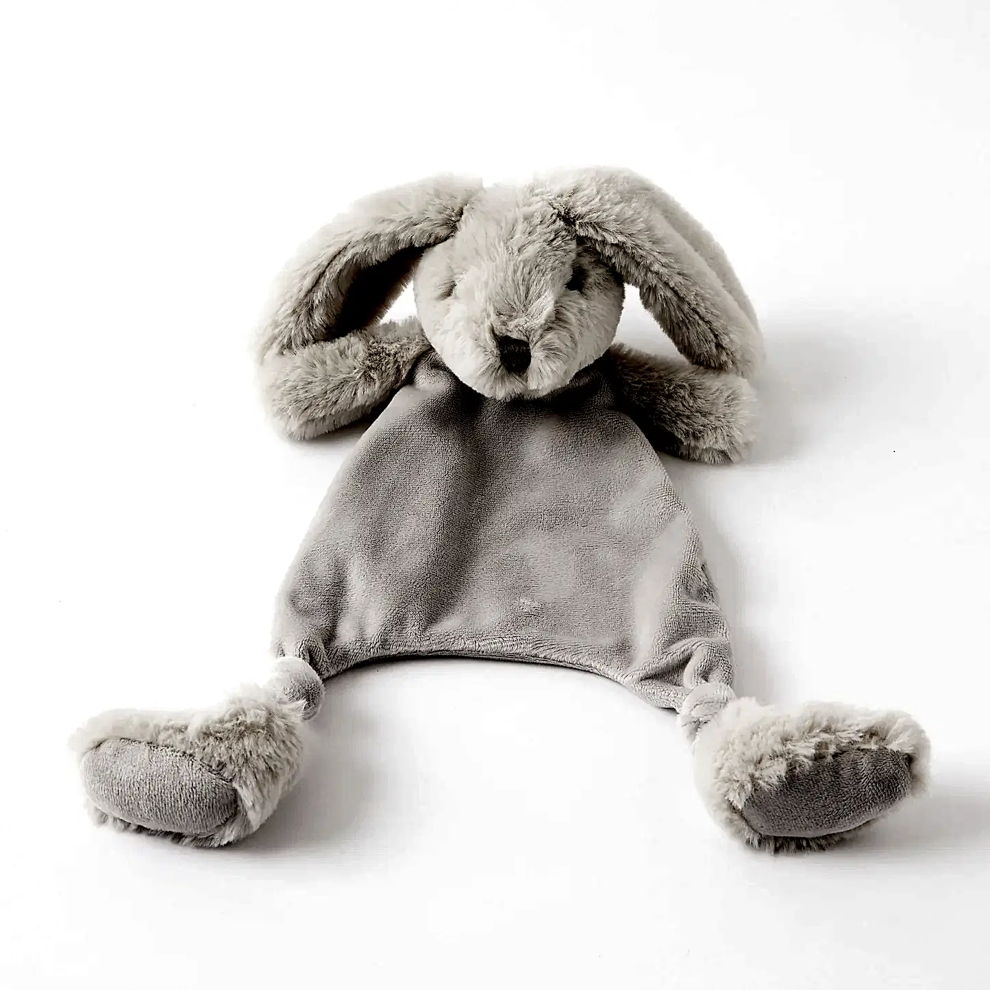 The Jiggle & Giggle Bunny Comforter by FlowersonNortonSt rests on a white background. With its soft, grey plush texture, floppy ears, and simple face, this ultra-soft bunny soother lacks arms or legs and features a small, flat body ending in rounded feet. It's the ideal comfort item for teething babies needing gentle solace.