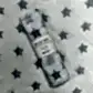 A rolled muslin wrap from FlowersonNortonSt is elegantly placed on a fabric background adorned with star patterns, enhancing the celestial theme. This soft muslin, featuring a matching star design, includes a label that reads "Muslin Wraps" and "100% cotton," making it ideal for baby wrapping.