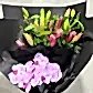 The "Colour Me - Pink" bouquet by Flowers on Norton St features seasonal pink flowers, including unopened lilies and light purple orchids, beautifully arranged against a black background—making it the perfect romantic gift.
