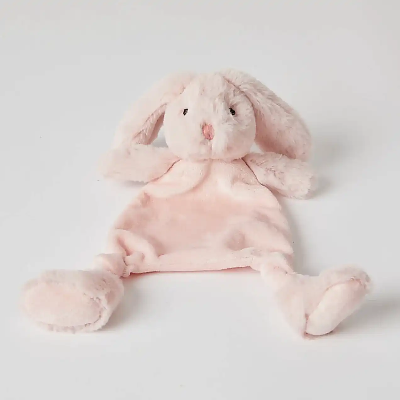 The Jiggle & Giggle Bunny Comforter by FlowersonNortonSt is a plush pink toy made from ultra-soft fabrics, designed with floppy ears and a simple embroidered face. It lies against a white background and is ideal for teething babies, featuring a flat body and rounded feet to provide both comfort and companionship.