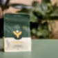 A package of "We The Wild - Plant Care" by FlowersonNortonSt, labeled "Support," contains slow-release plant food made by worms to strengthen roots naturally. The green and beige packaging rests on a green surface, with plant leaves artistically blurred in the background, ideal for naturally tackling pest issues.
