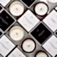 A display of Flowers on Norton St's Sohum Eco Cedarwick Candles features exquisite scents such as Tahitian Gardenia, Amber Rose, and Bourbon. Each candle is crafted with a botanical wax blend and a wooden wick, elegantly presented in sophisticated minimalist black and white packaging.