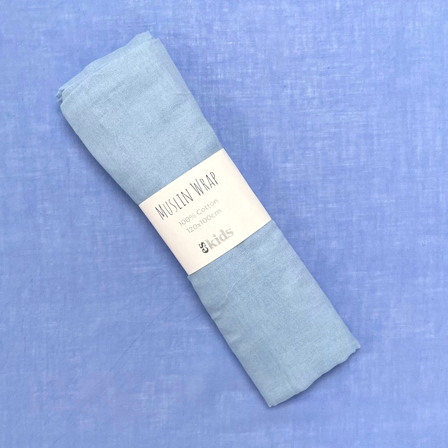 A folded light blue muslin wrap from FlowersonNortonSt, ideal for swaddling babies, features a label stating "Muslin Wraps, 100% cotton, 120x120cm." The gentle color of the soft muslin perfectly matches the light blue background.