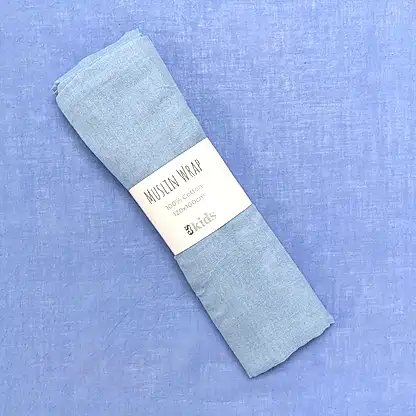 A folded light blue muslin wrap from FlowersonNortonSt, ideal for swaddling babies, features a label stating "Muslin Wraps, 100% cotton, 120x120cm." The gentle color of the soft muslin perfectly matches the light blue background.